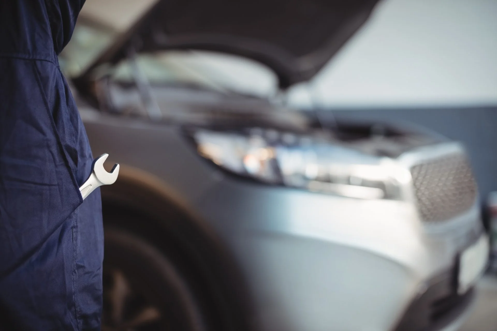 Detail servisní prohlídky vozu s klíčem v ruce mechanika